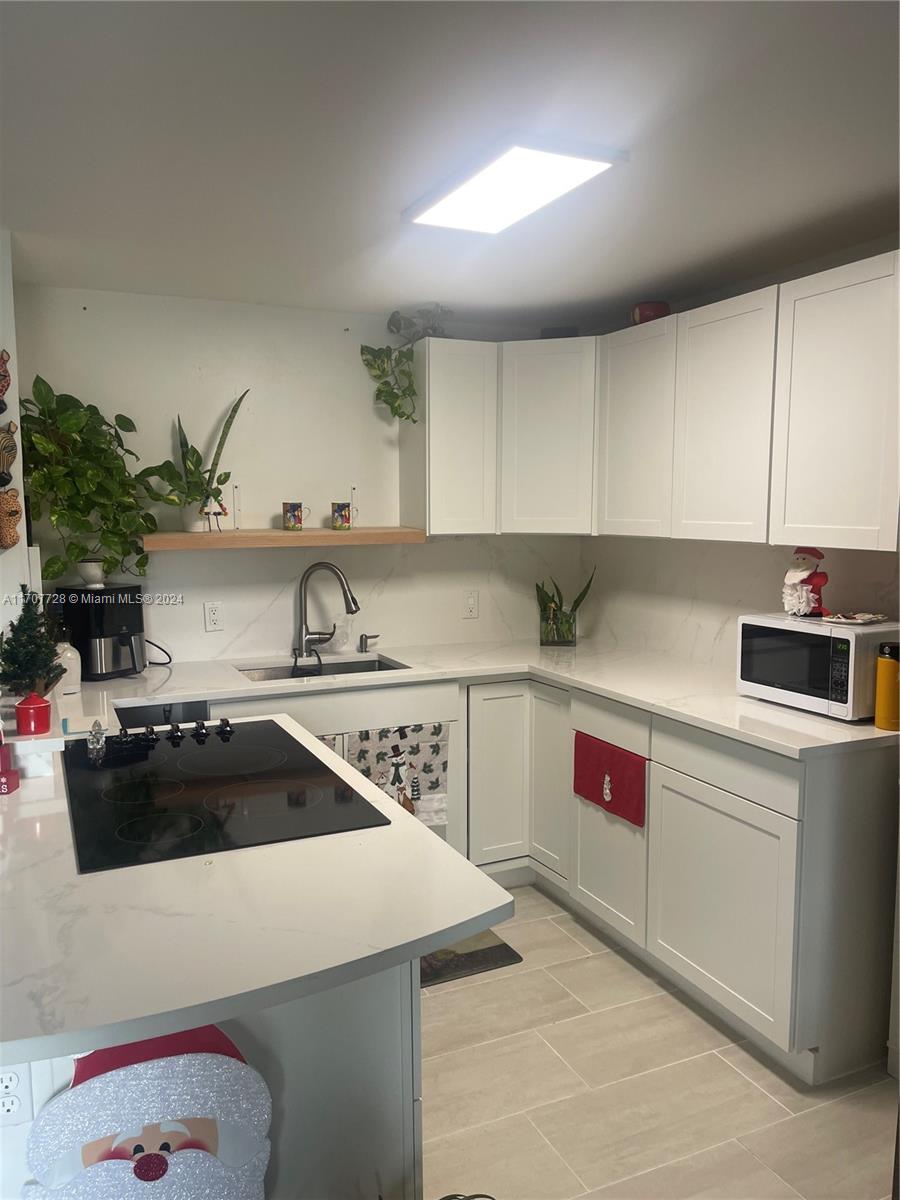 191 Prescott J, Unit 191 Deerfield Beach, FL 33442 - Photo 14 of 18 a kitchen with a sink a stove and cabinets