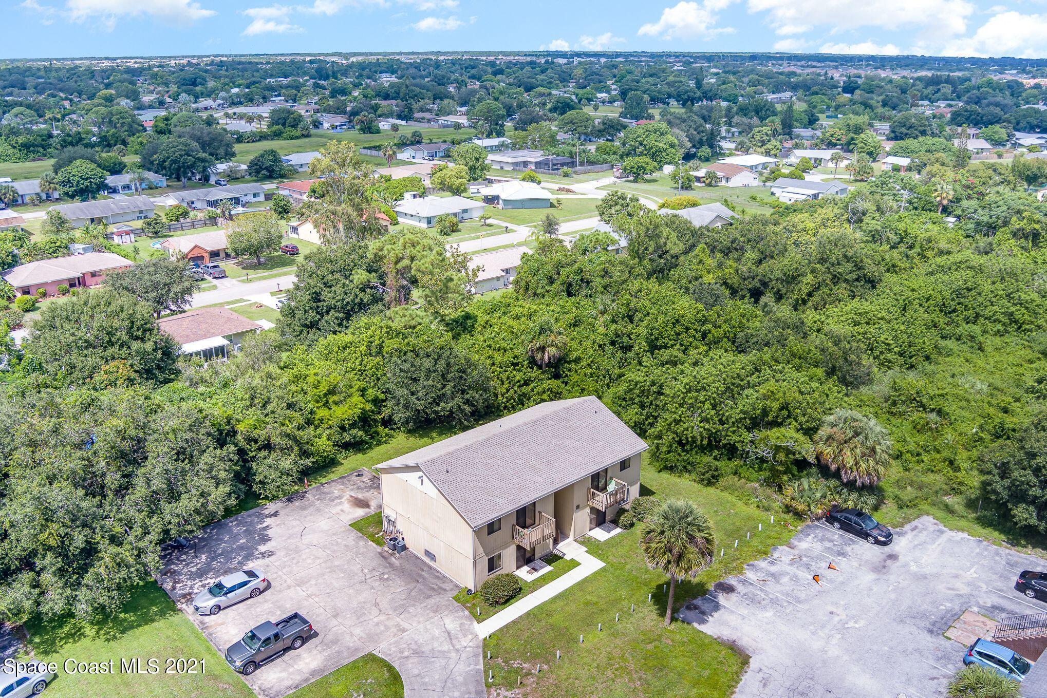 4313 Tree Ridge Lane Northeast Palm Bay, FL 32905 - Photo 2 of 9 an aerial view of residential houses with outdoor space and trees