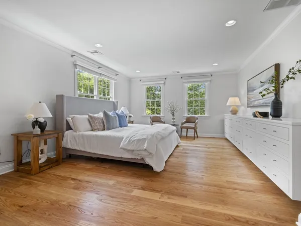 a spacious bedroom with a large bed and a flat tv screen on dresser