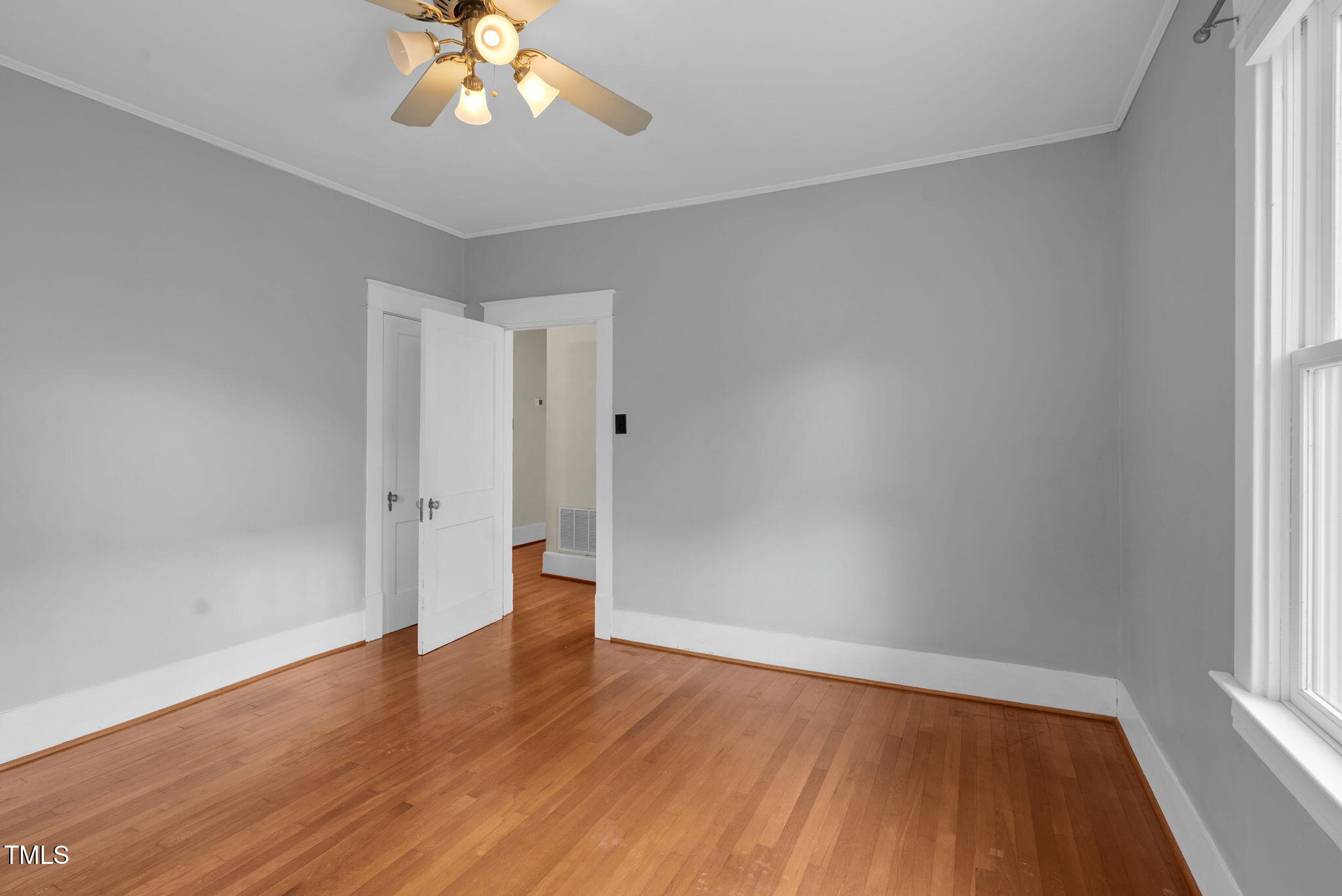 306 Perry Street Raleigh, NC 27608 - Photo 24 of 48 an empty room with wooden floor chandelier fan and windows