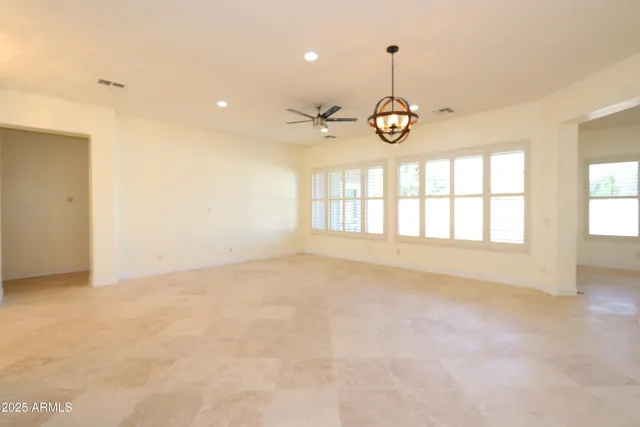 an empty room with windows and ceiling fan