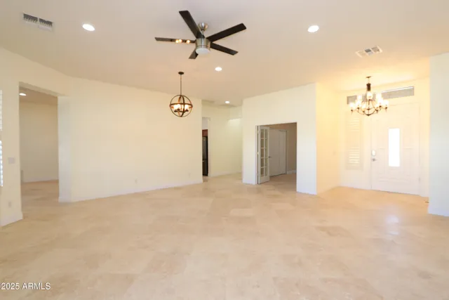 an empty room with a chandelier fan and a bathroom