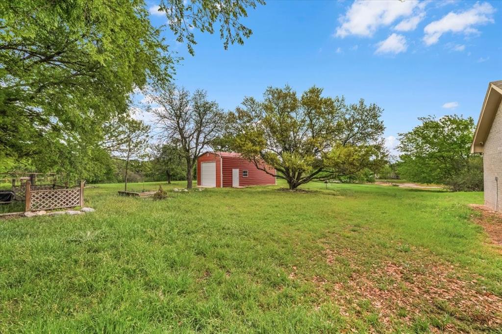 353 Hidden Meadow Court Rhome, TX 76078 - Photo 22 of 28 View of grassy yard with an outdoor structure and a detached garage