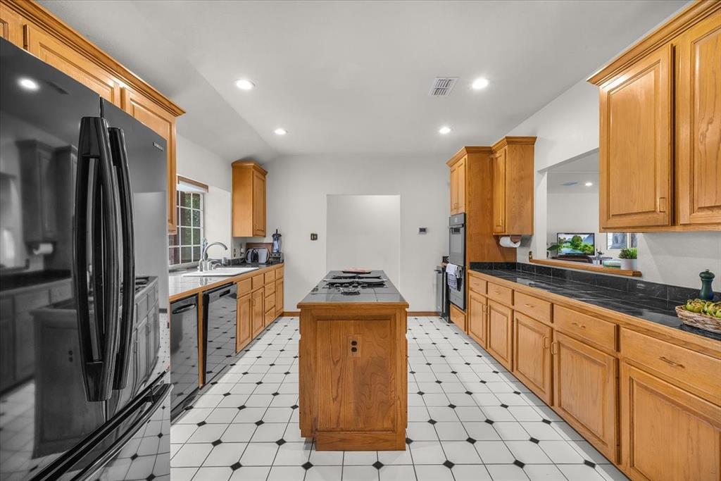 353 Hidden Meadow Court Rhome, TX 76078 - Photo 8 of 28 Kitchen with black appliances, a kitchen island, recessed lighting, dark countertops, and light floors