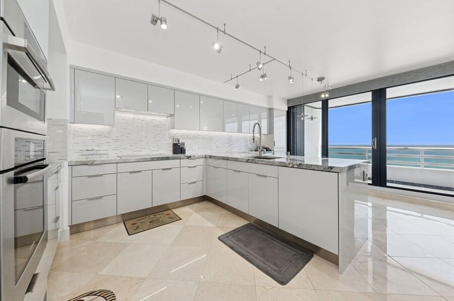 1400 South Ocean Boulevard, Unit 1004 Boca Raton, FL 33432 - Photo 8 of 55 a kitchen with white cabinets and white appliances