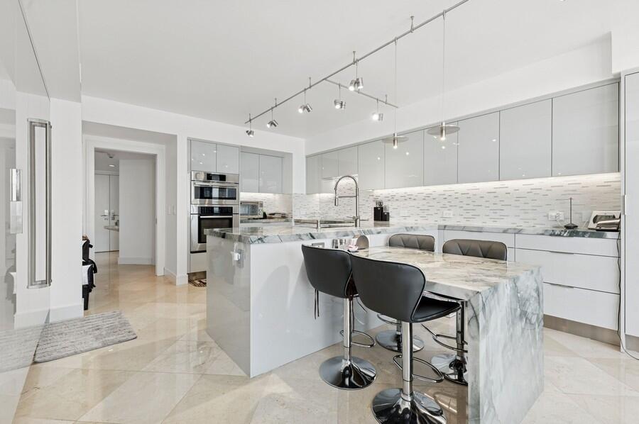 1400 South Ocean Boulevard, Unit 1004 Boca Raton, FL 33432 - Photo 10 of 55 a kitchen with stainless steel appliances kitchen island granite countertop a table chairs sink and cabinets