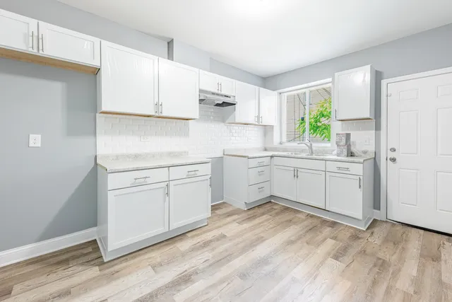 a kitchen with white cabinets sink and appliances