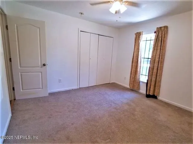 an empty room with windows and fan