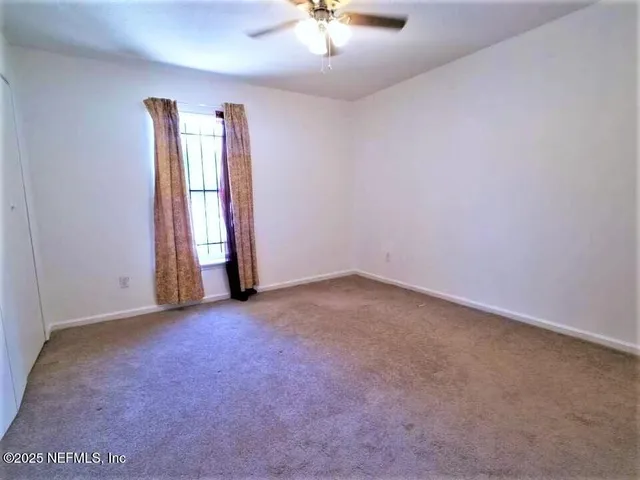 an empty room with windows and chandelier fan