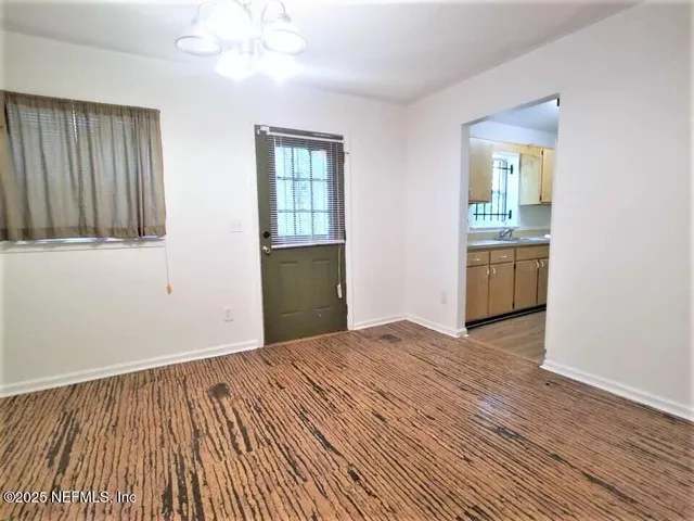 a view of an empty room with window and wooden floor