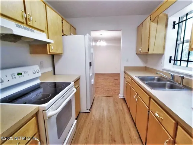a kitchen with granite countertop a sink a stove and refrigerator