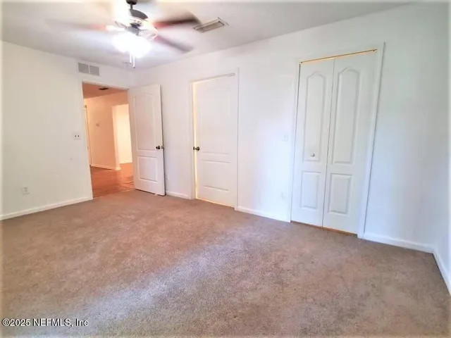 a view of an empty room and a ceiling fan