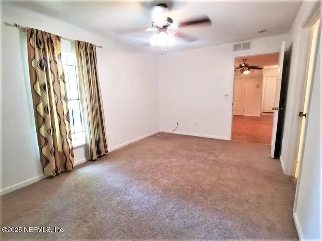 an empty room with windows and fan