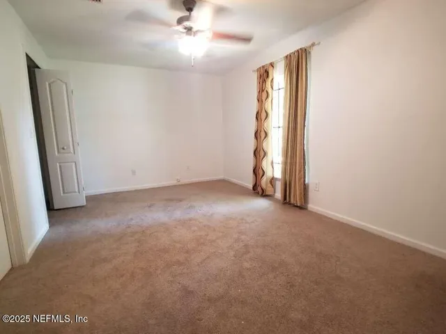 an empty room with windows and fan