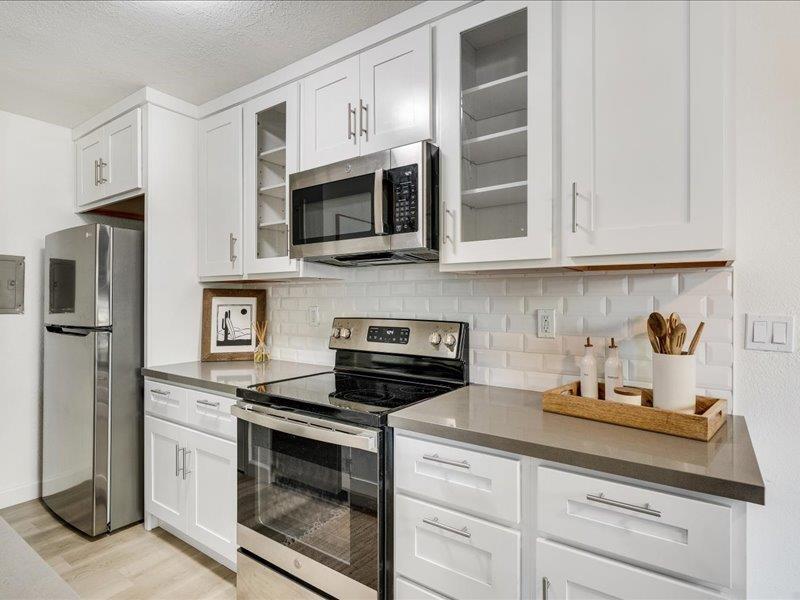 4475 Diamond Street, Unit 3 Capitola, CA 95010 - Photo 4 of 25 a kitchen with stainless steel appliances granite countertop white cabinets a stove a microwave and a refrigerator