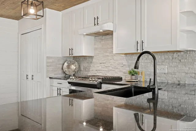 a kitchen with stainless steel appliances a sink a stove and white cabinets