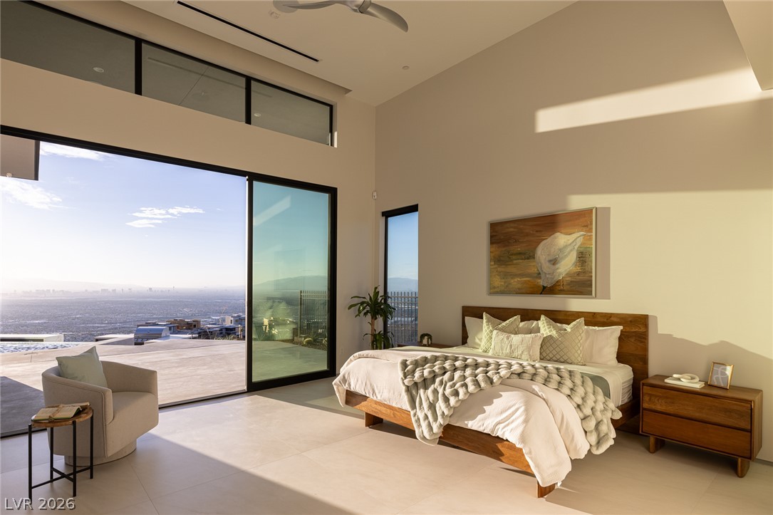 563 Grand Rim Drive Henderson, NV 89012 - Photo 28 of 70 Floor-to-ceiling glass doors reveal panoramic city views from this well-lit bedroom.