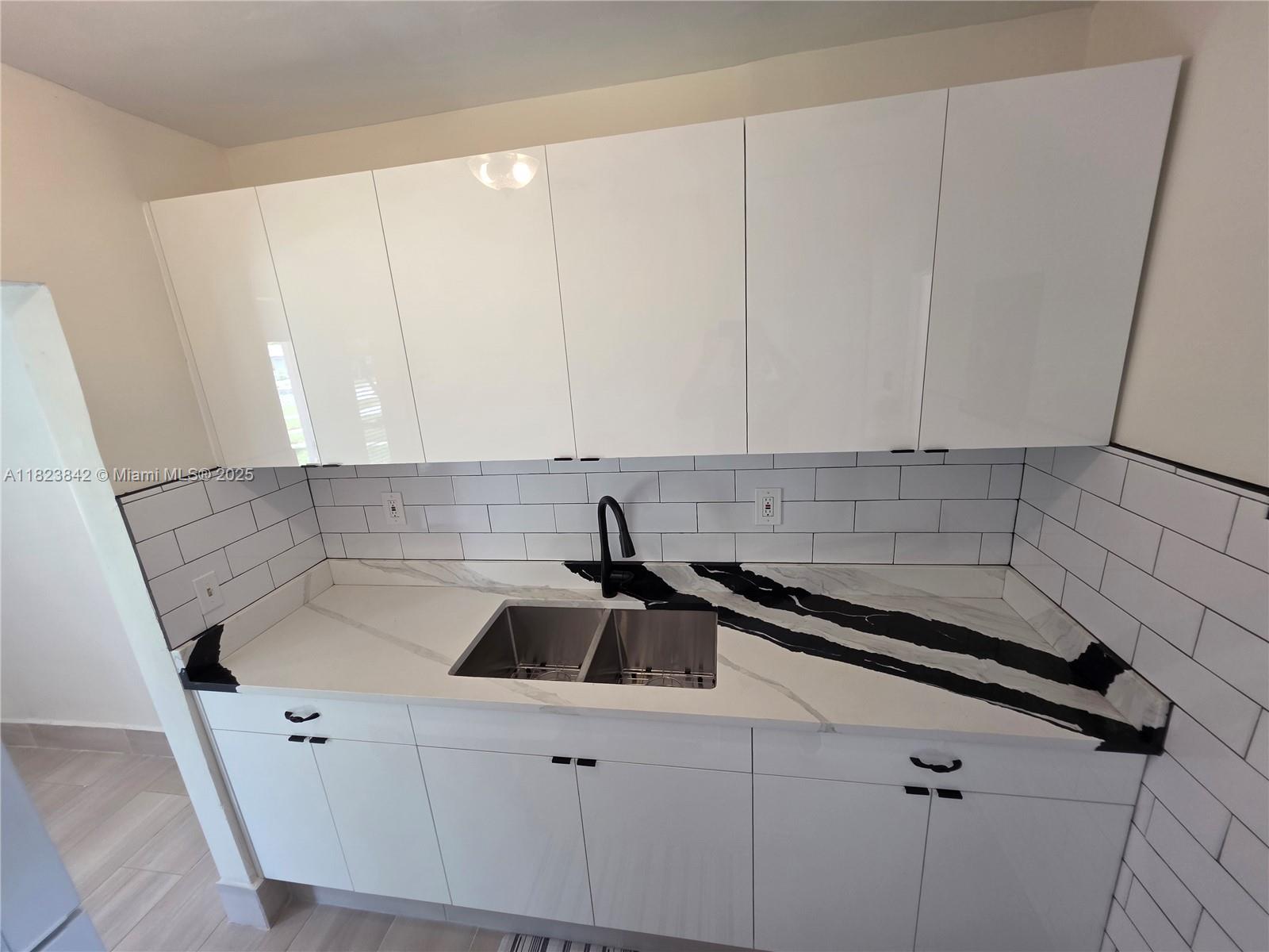 120 Northeast 10th Avenue, Unit 3 Hallandale Beach, FL 33009 - Photo 3 of 11 a kitchen with a sink and cabinets