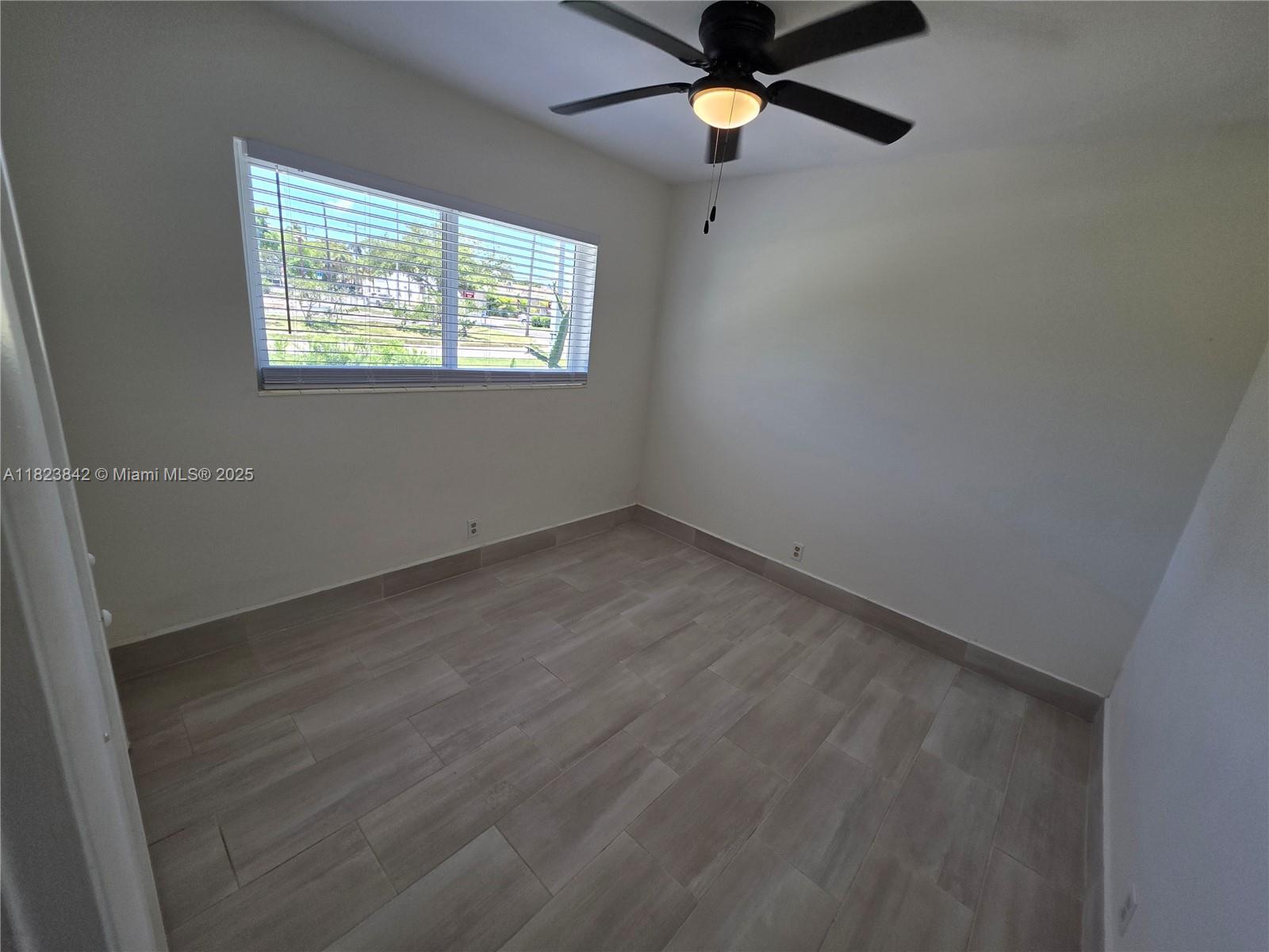 120 Northeast 10th Avenue, Unit 3 Hallandale Beach, FL 33009 - Photo 6 of 11 an empty room with windows and fan