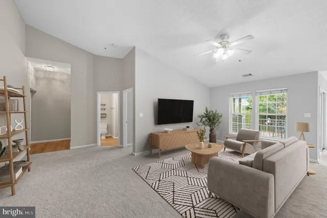 a living room with furniture a flat screen tv and a large window
