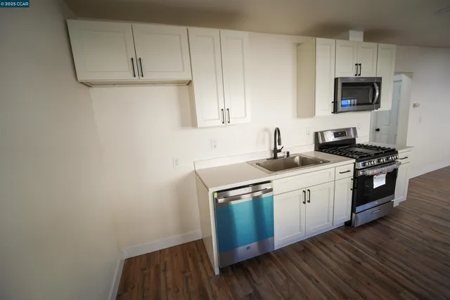 a kitchen with granite countertop a sink cabinets and stainless steel appliances