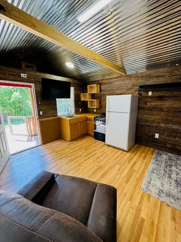 a living room with stainless steel appliances kitchen island furniture and a wooden floor