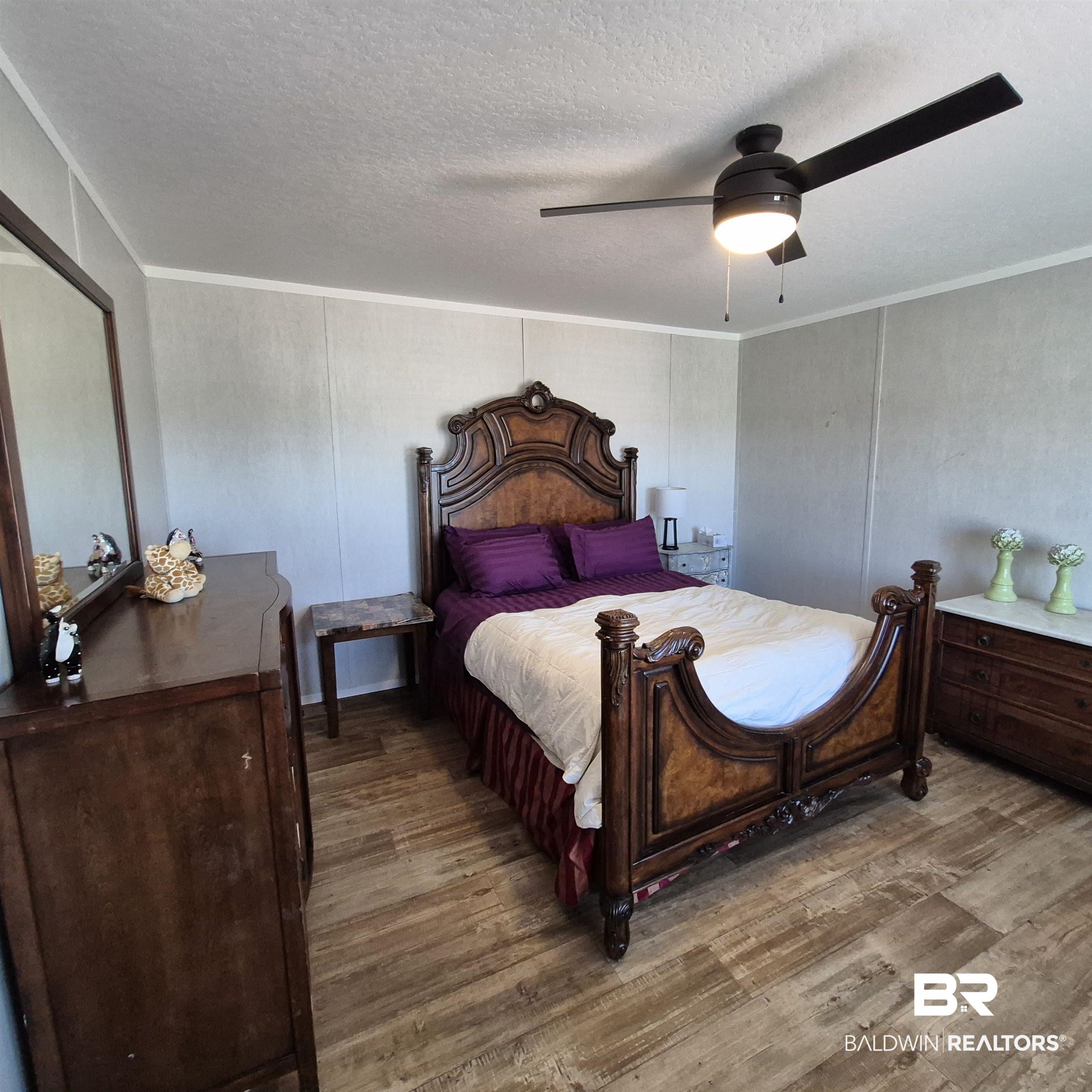 8867 Old Stage Road Repton, AL 36475 - Photo 15 of 37 Bedroom featuring a ceiling fan, dark wood finished floors, a decorative wall, a textured ceiling, and ornamental molding