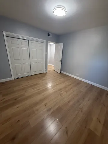 an empty room with wooden floor and closet area