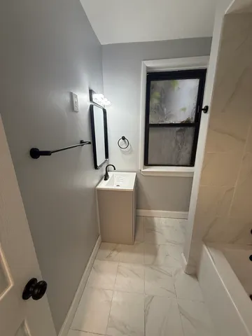 a bathroom with a tub sink and mirror