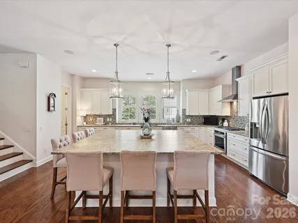 a large kitchen with granite countertop a dining table chairs wooden floor and appliances
