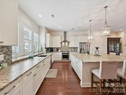 a large kitchen with granite countertop lots of counter space sink and a chandelier