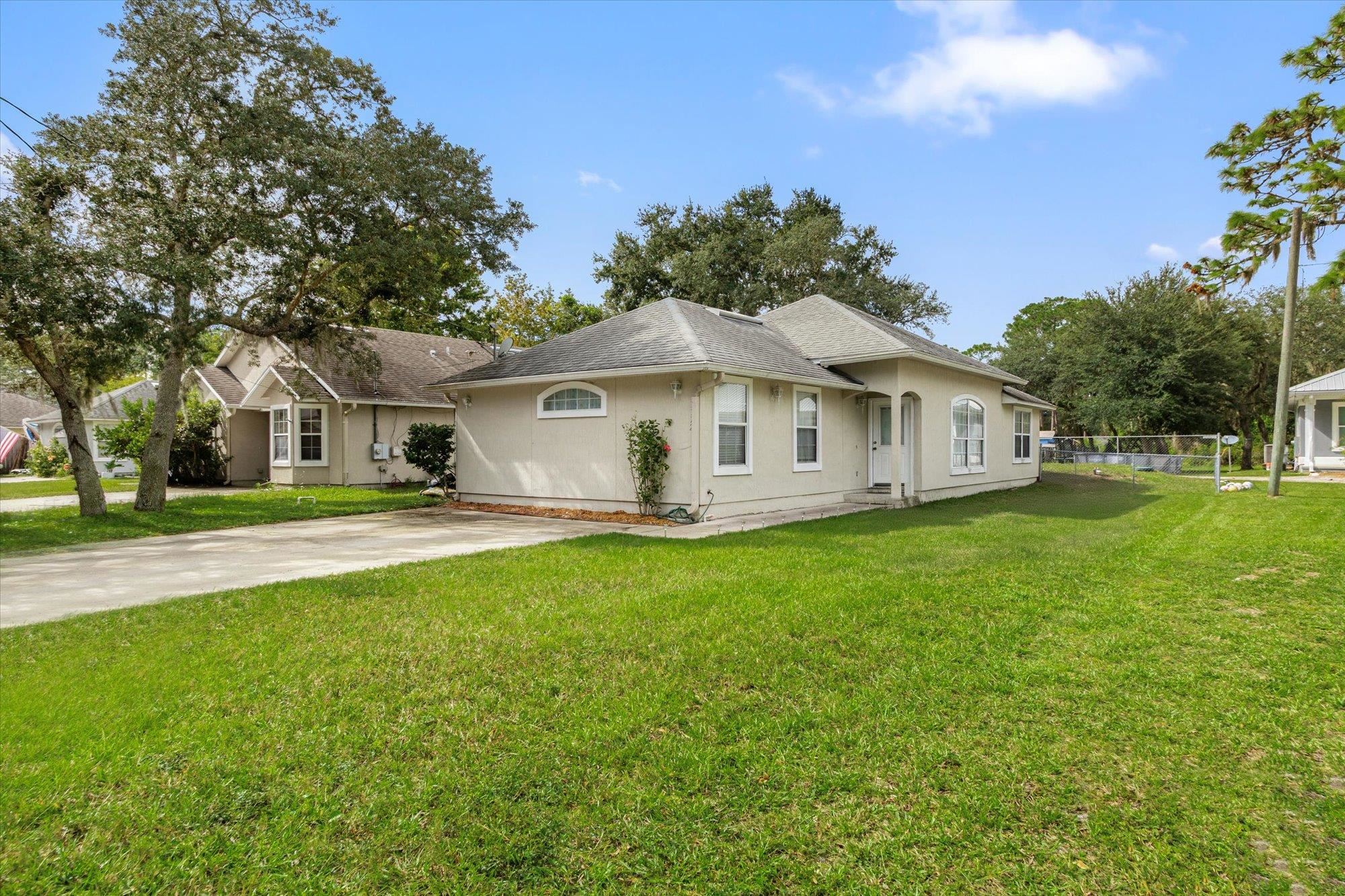 3372 4th Street Elkton, FL 32033 - Photo 24 of 36 a view of a white house with a big yard plants and large trees