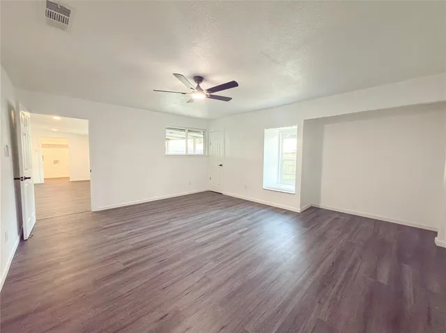 an empty room with wooden floor and windows