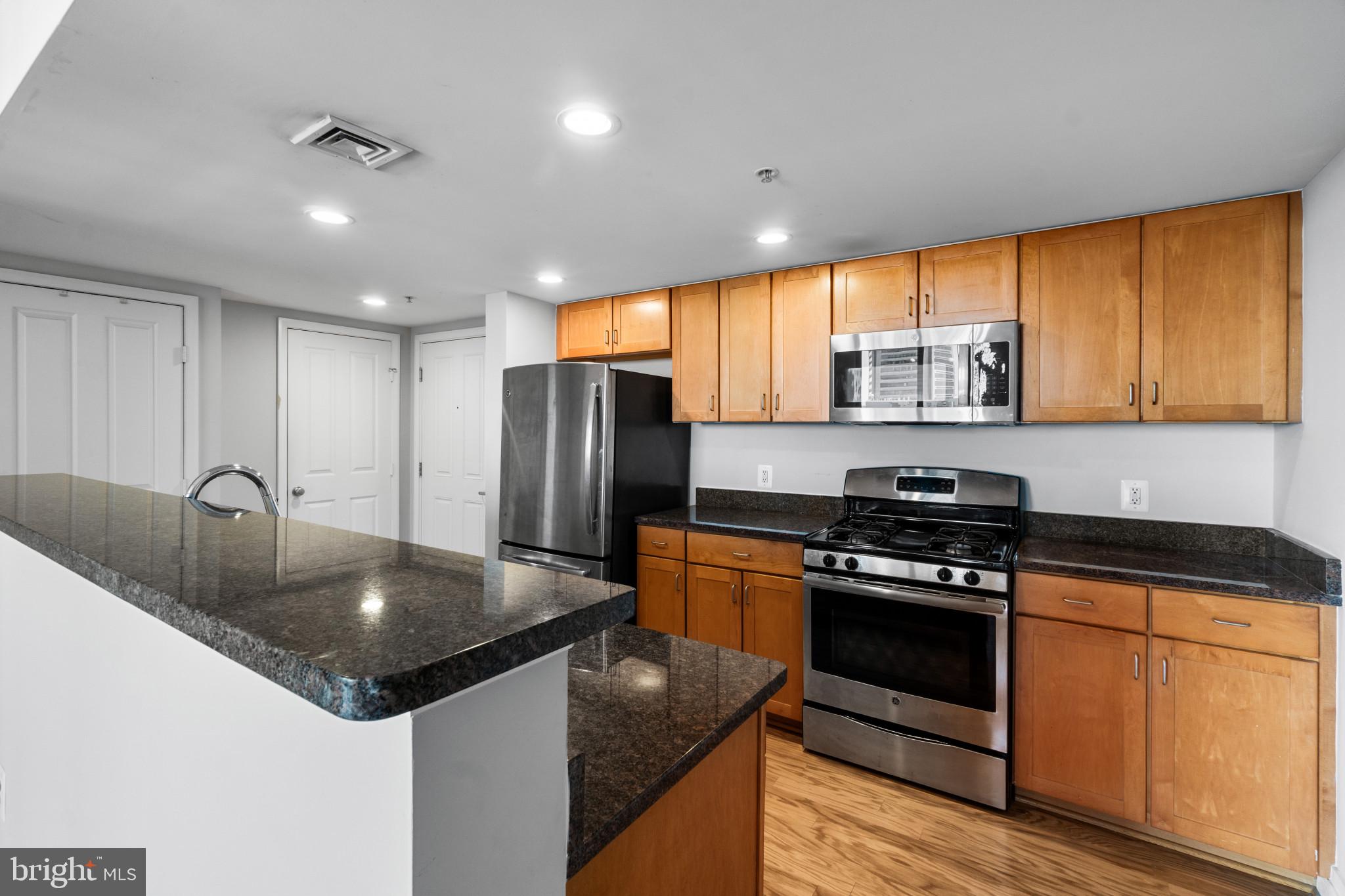 414 Water Street, Unit 1315 Baltimore, MD 21202 - Photo 7 of 30 a kitchen with stainless steel appliances granite countertop a sink a stove and a refrigerator