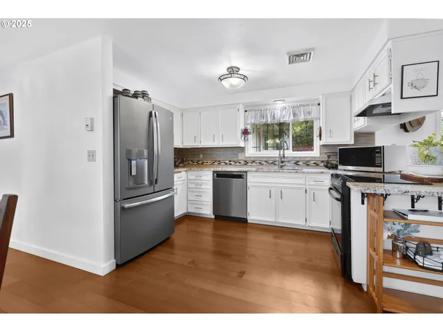 a kitchen with stainless steel appliances granite countertop a stove top oven a refrigerator and a sink
