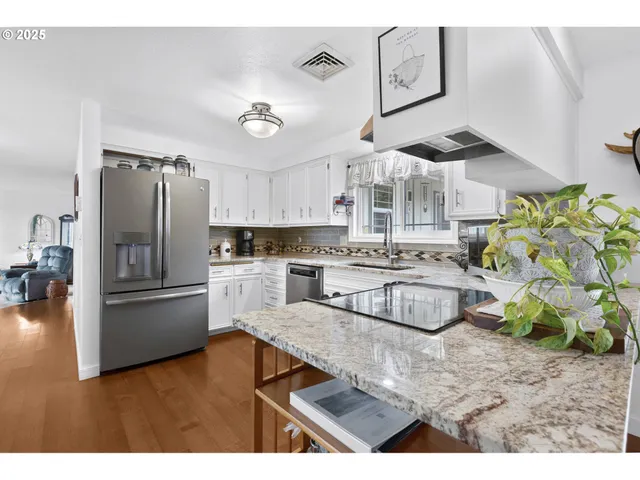 a kitchen with stainless steel appliances granite countertop a refrigerator a stove and a sink