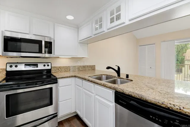 a kitchen with granite countertop a sink dishwasher stove and microwave with wooden floor
