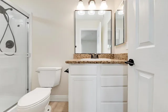 a bathroom with a granite countertop toilet sink and mirror