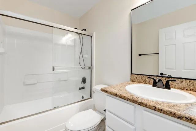 a bathroom with a granite countertop sink toilet and shower