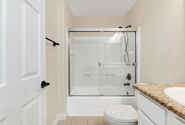 a bathroom with a granite countertop shower a toilet and a sink