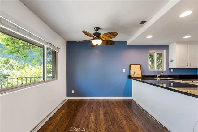 a kitchen with stainless steel appliances granite countertop a sink a microwave oven a refrigerator and white cabinets with wooden floor