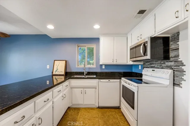 a kitchen with granite countertop white cabinets and window