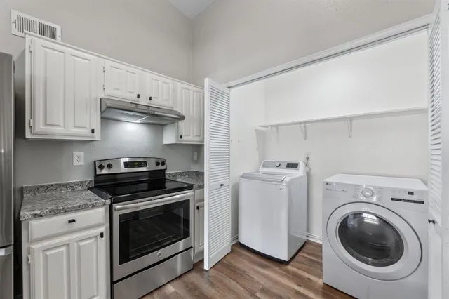 a kitchen with cabinets stainless steel appliances and wooden floor