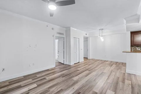 a view of empty room with wooden floor and fan
