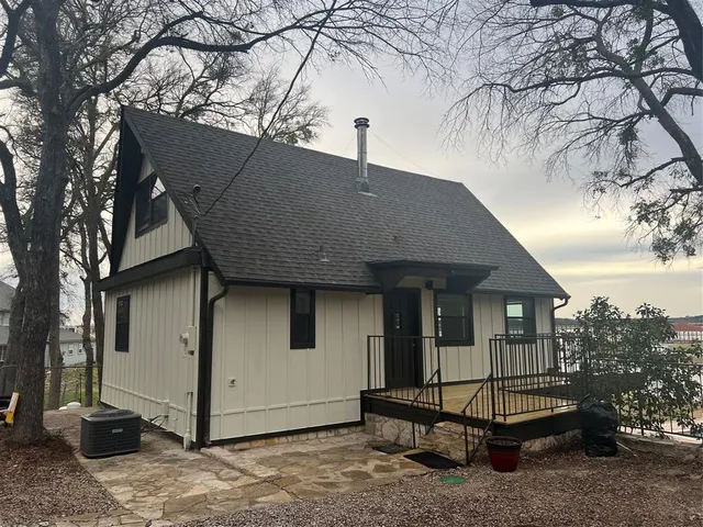 a backyard of a house with barbeque oven and large tree