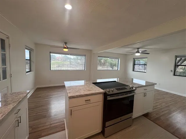 a view of an empty room with wooden floor and a ceiling fan