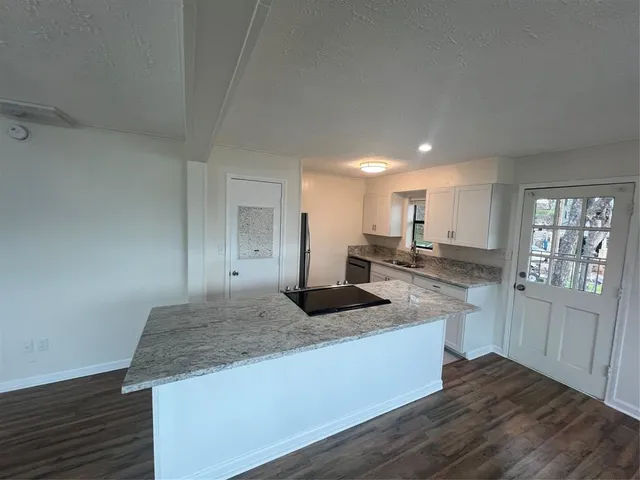 a large kitchen with granite countertop a sink and cabinets