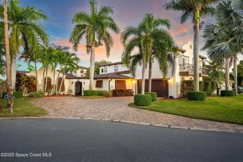 a front view of house with small garden and palm trees