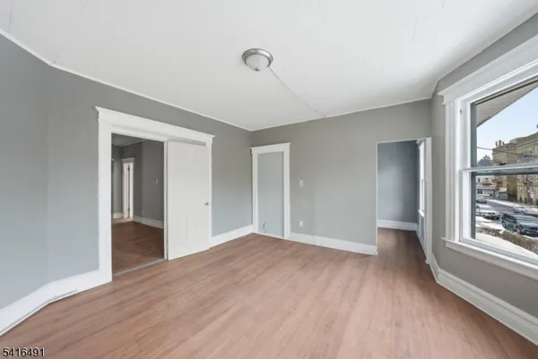 a view of an empty room with window and wooden floor