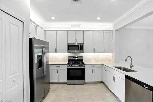 a kitchen with white cabinets and stainless steel appliances